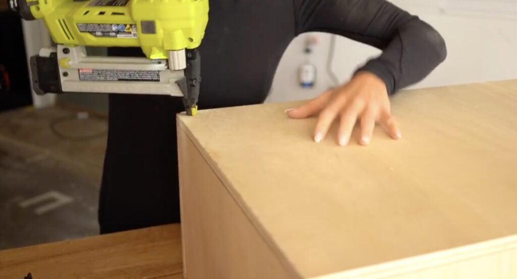 Stapling the top plywood panel securely to the bench frame.